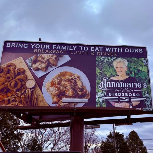 Annamarie's on Main billboard featuring food, the owner, and text "Bring Your Family to Eat With Ours".