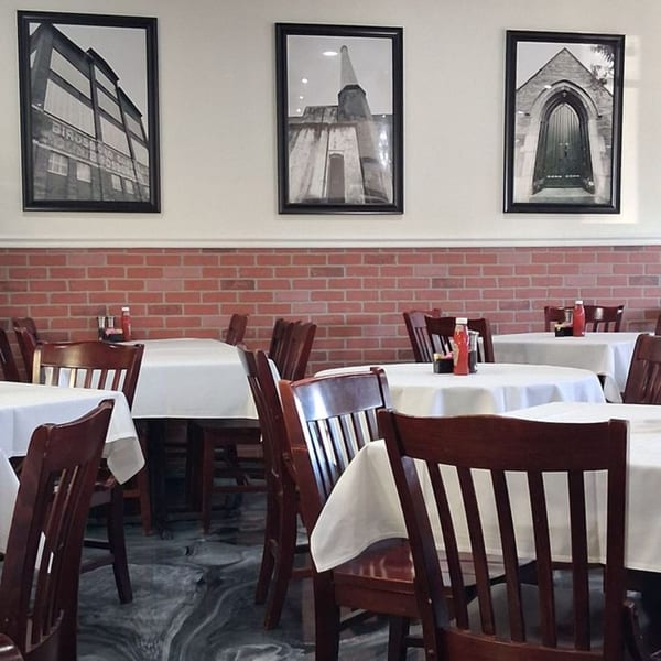 Annamarie's on Main dining room with white tablecloths, dark wooden chairs, and brick wainscoting.